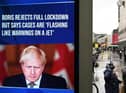 A news display features Britain's Prime Minister Boris Johnson as shoppers make their way along the streets of Manchester