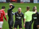 The Latics players surround referee Ollie Yates at Charlton