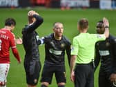 The Latics players surround referee Ollie Yates at Charlton