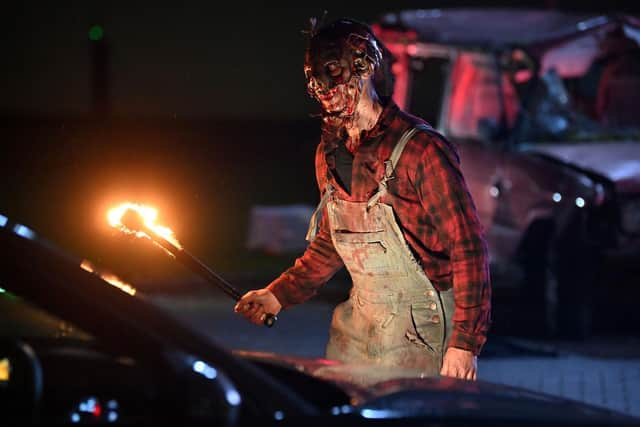 An actor dressed as a character from a horror movie scares people as they watch a horror film at a temporary drive in cinema in Manchester