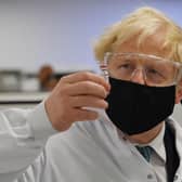 Britain's Prime Minister Boris Johnson poses for a photograph with a vial of the AstraZeneca/Oxford University COVID-19 candidate vaccine, known as AZD1222, at Wockhardt's pharmaceutical manufacturing facility in Wrexham, north Wales, on November 30, 2020.
