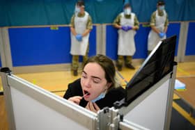 A woman undertakes a swab test at a temporary COVID-19 testing site at a leisure centre