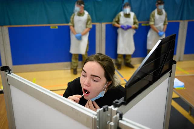 A woman undertakes a swab test at a temporary COVID-19 testing site at a leisure centre