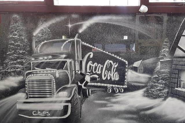 A snow art window design featuring the Coca Cola trucks