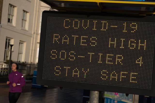 A member of public walks past a public safety notice that reads "Covid-19 Rates High, SOS-Tier 4, Stay Safe" on the high street on December 20, 2020 in Southend on Sea.