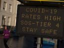 A member of public walks past a public safety notice that reads "Covid-19 Rates High, SOS-Tier 4, Stay Safe" on the high street on December 20, 2020 in Southend on Sea.