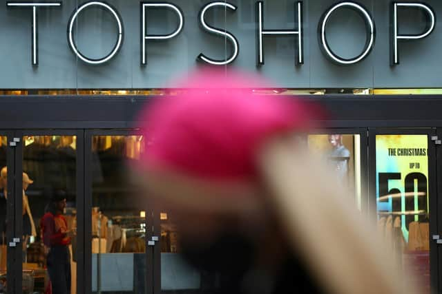 A pedestrian walks past Topshop clothes store.