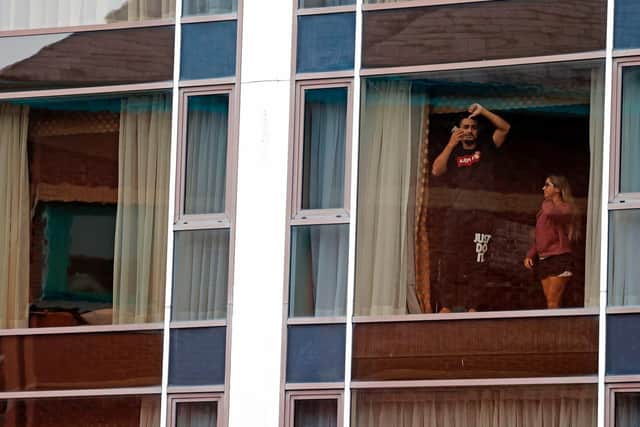 Travellers gestures as they look out of a window during mandatory hotel quarantine in a Radisson Blu hotel at Heathrow Airport
