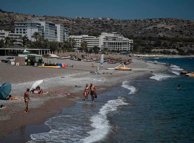 Tourists walk the beach in front of hotels on the Aegean island of Rhodes