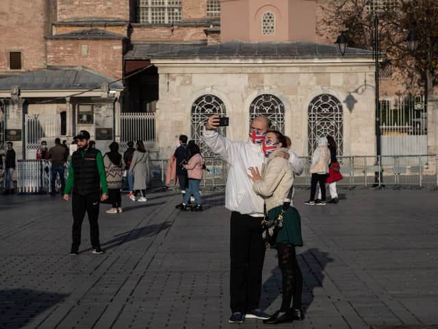 Tourists take a selfie in front of the Hagia Sophia Grand Mosque during a national weekend coronavirus lockdown on December 06, 2020, in Istanbul, Turkey