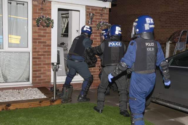 Police bash down a door during the operation (Image: GMP)