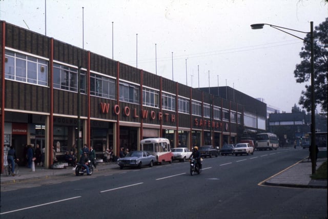 The Arndale Centre in 1977. Shops include Woolworth and Safeway, whose names are displayed along the top, as well as a number of smaller stores. The junction with Dennistead Crescent is on the right and Wood Lane is at the far end of the shopping centre.