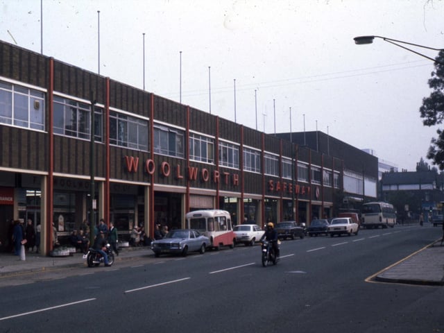 The Arndale Centre in 1977. Shops include Woolworth and Safeway, whose names are displayed along the top, as well as a number of smaller stores. The junction with Dennistead Crescent is on the right and Wood Lane is at the far end of the shopping centre.
