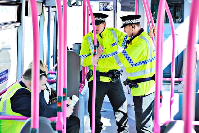 Police officers speak to a passenger on a bus