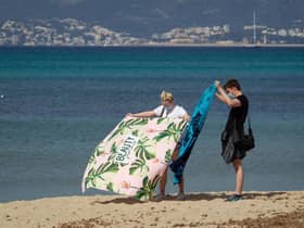 A tourist couple unfold their towels on Palma Beach in Palma de Mallorca
