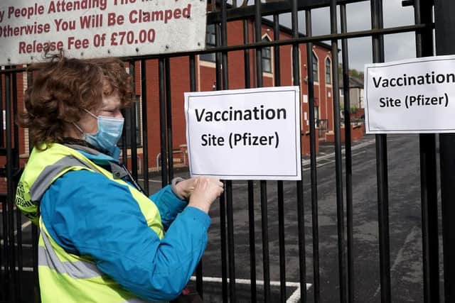A volunteer gives puts up signs outside a mobile vaccination clinic set up at the Masjid E Sajedeen Mosque in Little Harwood on May 24, 2021 in Blackburn