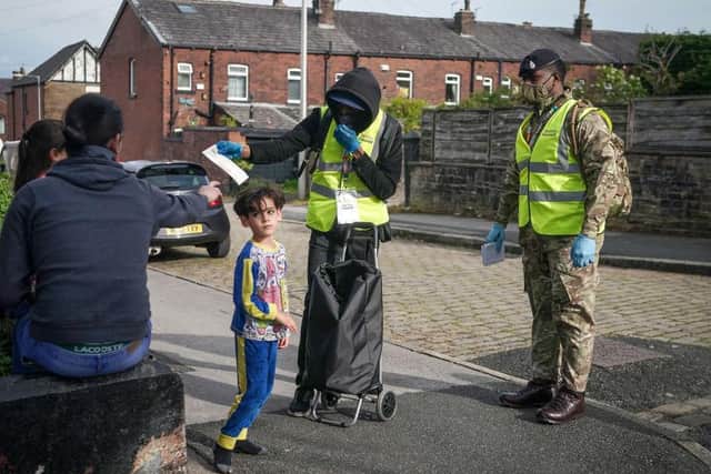 Children play in the street as gunners from the Royal Horse Artillery distribute Covid-19 polymerase chain reaction (PCR) tests to local residents in Bolton
