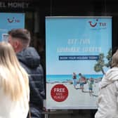 People make their way past the shop window of a Tui store