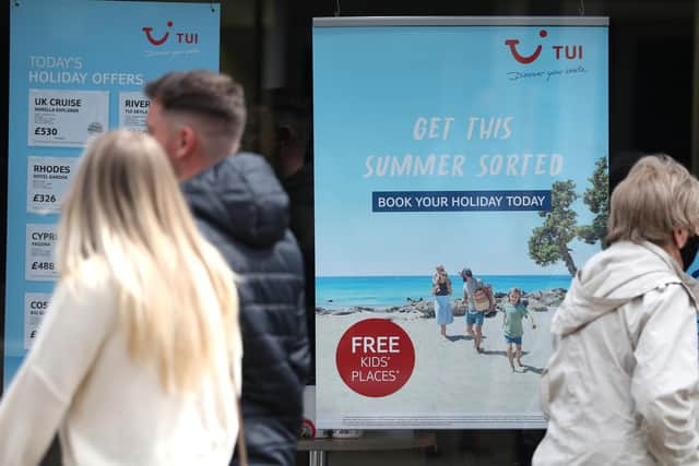 People make their way past the shop window of a Tui store