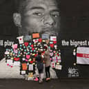 People placing messages of support on the mural of Marcus Rashford