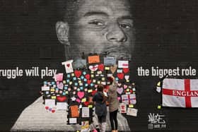 People placing messages of support on the mural of Marcus Rashford