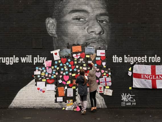 People placing messages of support on the mural of Marcus Rashford