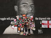People placing messages of support on the mural of Marcus Rashford