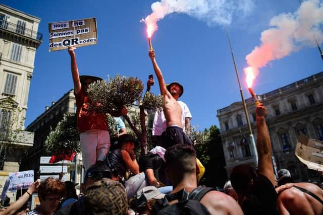 A protestor holds a placard reading "We are not QR codes" during a demonstration against the new coronavirus safety measures including a compulsory health pass called for by the French government, in Marseille on July 17 (Photo by CLEMENT MAHOUDEAU/AFP via Getty Images)