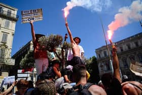 A protestor holds a placard reading "We are not QR codes" during a demonstration against the new coronavirus safety measures including a compulsory health pass called for by the French government, in Marseille on July 17 (Photo by CLEMENT MAHOUDEAU/AFP via Getty Images)