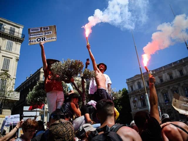A protestor holds a placard reading "We are not QR codes" during a demonstration against the new coronavirus safety measures including a compulsory health pass called for by the French government, in Marseille on July 17 (Photo by CLEMENT MAHOUDEAU/AFP via Getty Images)