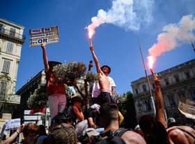 A protestor holds a placard reading "We are not QR codes" during a demonstration against the new coronavirus safety measures including a compulsory health pass called for by the French government, in Marseille on July 17 (Photo by CLEMENT MAHOUDEAU/AFP via Getty Images)
