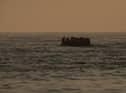 An inflatable craft carrying migrant men, women and children crosses the shipping lane in the English Channel.