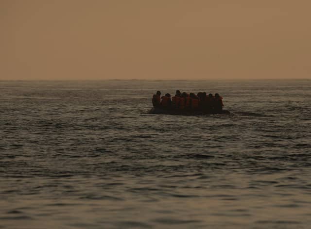 An inflatable craft carrying migrant men, women and children crosses the shipping lane in the English Channel.