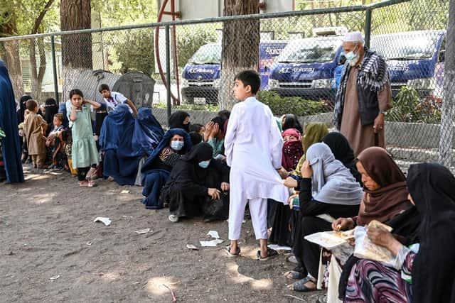 Internally displaced Afghan families, who fled from Kunduz and Takhar province due to battles between Taliban and Afghan security forces, eat their lunch at the Shahr-e-Naw Park in Kabul on August 10, 2021