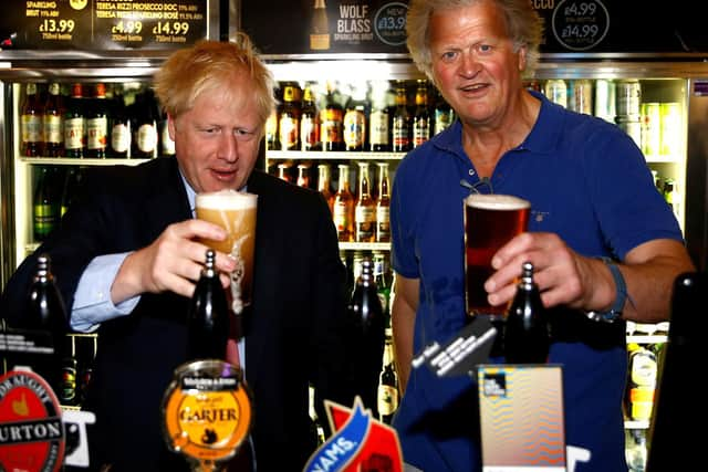 Boris Johnson (L) poses with a pint of beer as he talks with JD Wetherspoon chairman Tim Martin during his visit to their Metropolitan Bar in London, on July 10, 2019.