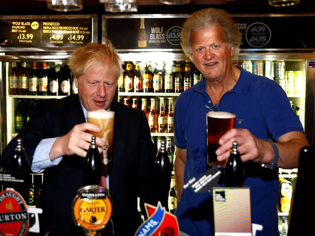 Boris Johnson (L) poses with a pint of beer as he talks with JD Wetherspoon chairman Tim Martin during his visit to their Metropolitan Bar in London, on July 10, 2019.