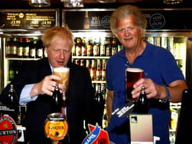 Boris Johnson (L) poses with a pint of beer as he talks with JD Wetherspoon chairman Tim Martin during his visit to their Metropolitan Bar in London, on July 10, 2019.