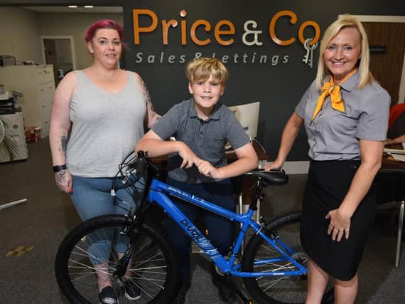 Victoria Matthews and son George collect the new bicycle from Yvonne Howe, representing Price and Co