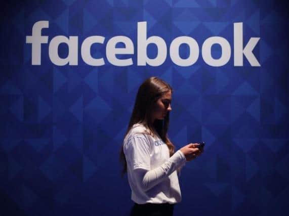 Library image of a woman using her phone under a logo of Facebook. Facebook has blamed a “faulty configuration change” for the widespread outage which impacted the social media platform, along with Instagram and WhatsApp, for several hours late on Monday