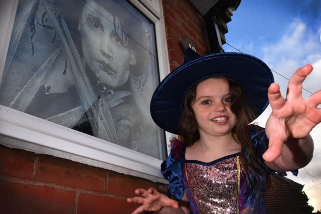 Maisie Wilcock, eight, getting into the spirit of Halloween as her dad, Snow Graffiti artist Scott Wilcock has created window displays for Halloween at his home in Ashton-in-Makerfield.