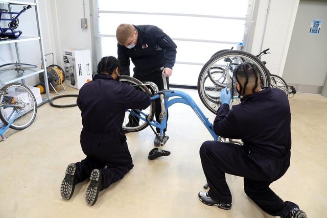 Inmates - residents - work on a Brackmills 'Boris' bike with a warden.