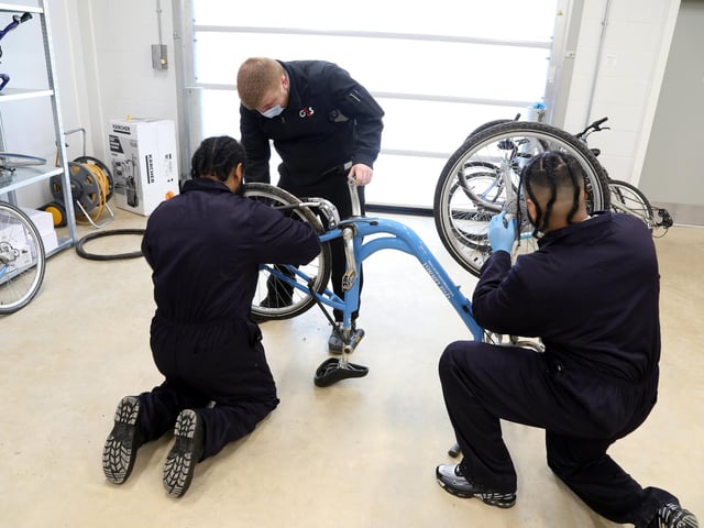 Inmates - residents - work on a Brackmills 'Boris' bike with a warden.