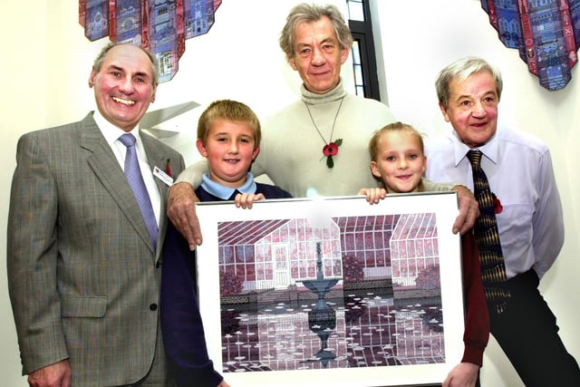 Sir Ian McKellen receives a Gerald Rickards painting of the lily pond at Haigh Hall from Daniel Pye from Holgate Primary School and Emma Beardsworth from Hindley Junior and Infants School watched by chairman of the hospice trustees, Gordon Valentine, and artist Gerald Rickards.
