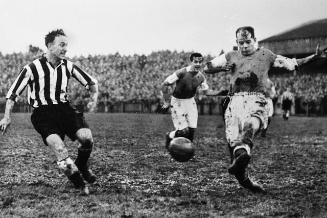 Wigan Athletic left half Kenny Banks blocks a Newcastle United attack with left back Harry Parkinson in the background.
