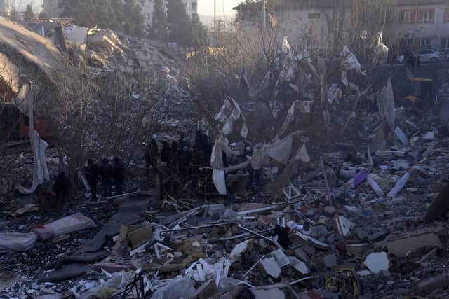 People stand near a collapsed building as rescuers search for their relatives in Kahramanmaras,