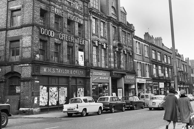 The Queens Hall Methodist Mission and the derelict W.H.S. Taylor food depot on Market Street, Wigan, in 1966.
Other shops in the row are Elizabeth Wilding Cameras, C. Kershaw Opthalmic Opticians, JDR Cameras, Schofields shoe shop, Singer sewing machine shop and Coombes shoe repairs.