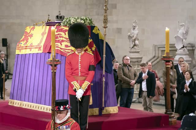 The coffin of Queen Elizabeth II, draped in the Royal Standard with the Imperial State Crown and the Sovereign's orb and sceptre, lying in state on the catafalque in Westminster Hall, at the Palace of Westminster, London, ahead of her funeral on Monday.