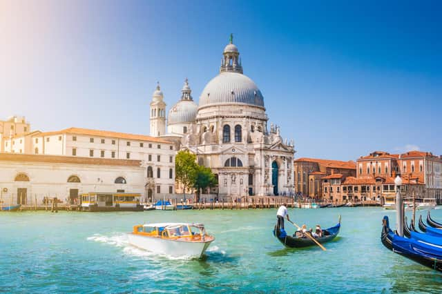 Beautiful view of traditional Gondola on Canal Grande with historic Basilica di Santa Maria della Salute in the background on a sunny day in Venice, Italy