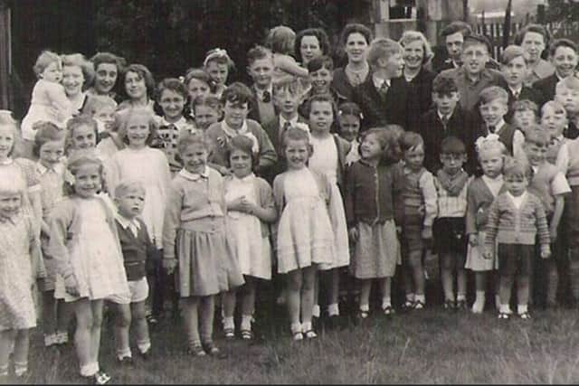The group photo is of children and mums from Smalley Street and adjoining Collingwood Street outside a large wooden hut off Preston Road used for social events. The children were given a Coronation mug and bar of chocolate in a celebration tin. Many of the young faces are still living in and around Standish. Others have moved throughout the UK and abroad.