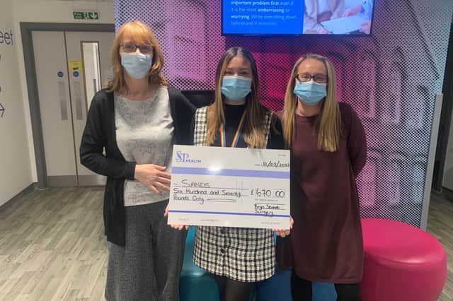 Staff at Bryn Street GP practice holding up a cheque with the funds they are donating to charity.